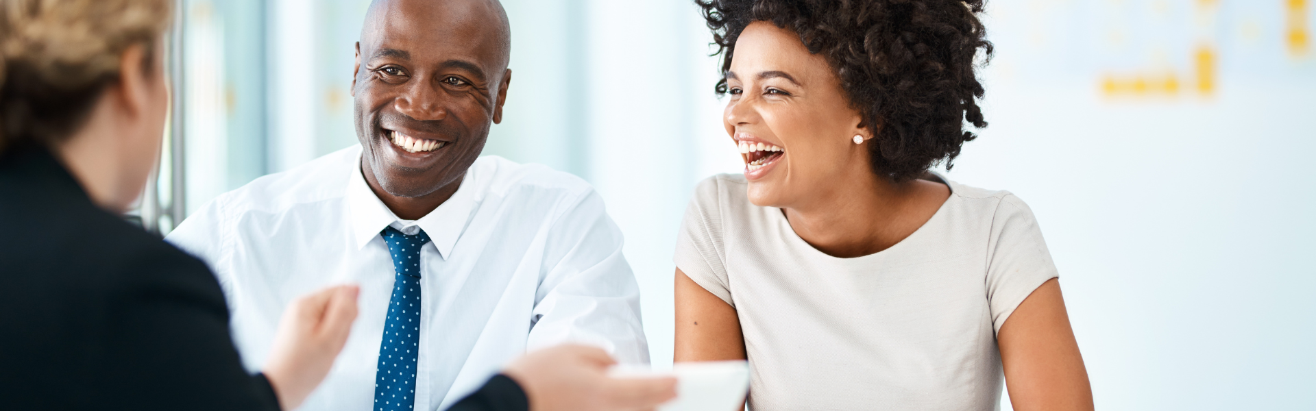 Young couple smiling during meeting with sales person.